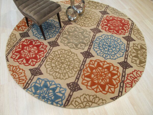 A round, neutral rug with red, blue, green, and orange floral medallions rests on light wood flooring.