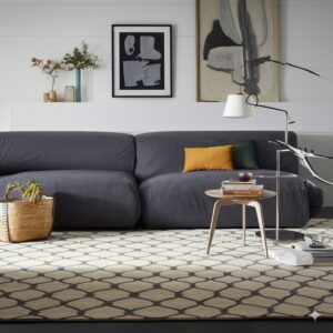 Beige rug with a dark geometric lattice pattern anchoring a living room with a large gray sofa.