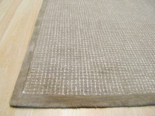 Textured beige rug featuring an irregular grid pattern and a uniform taupe border on light wood floor.