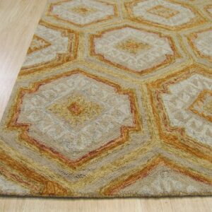 Beige rug featuring interlocking geometric hexagons outlined in shades of gold and rust on light wood flooring.