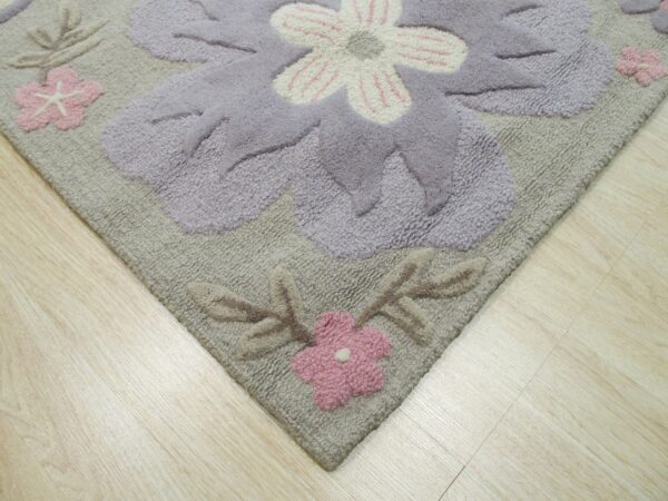 High-pile rug with large carved lavender and pink flowers lies on light wood flooring.