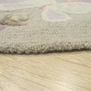 Textured beige area rug with dimensional pink and lavender designs rests on light wood planks.