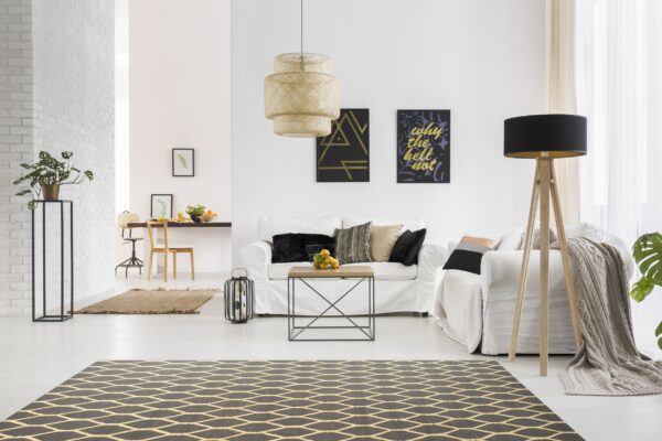 Black and gold diamond rug under a modern coffee table in a bright white living room.