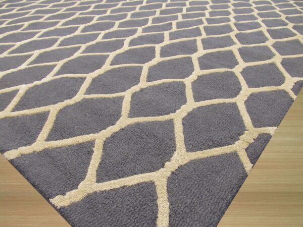 Dark gray rug with a contrasting textured high-low beige geometric pattern resting on light wood floor.