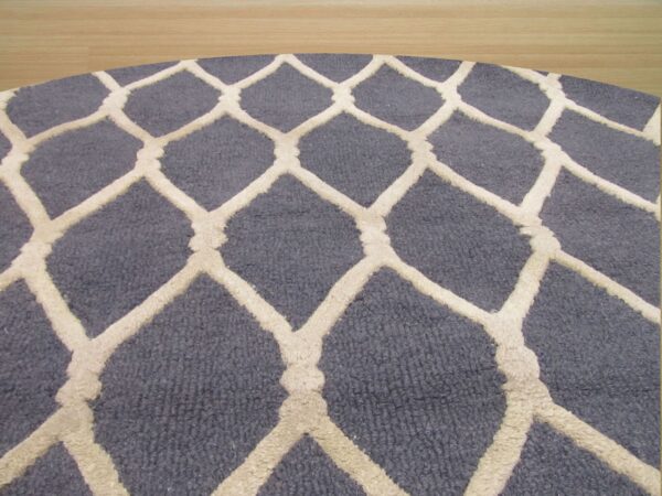 Curved blue rug with raised off-white diamond trellis pattern visible against light wood floor.