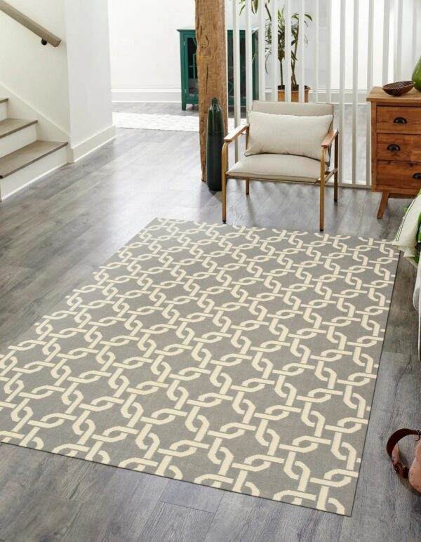 Gray rug with a cream trellis pattern lying on wood flooring next to a modern armchair.