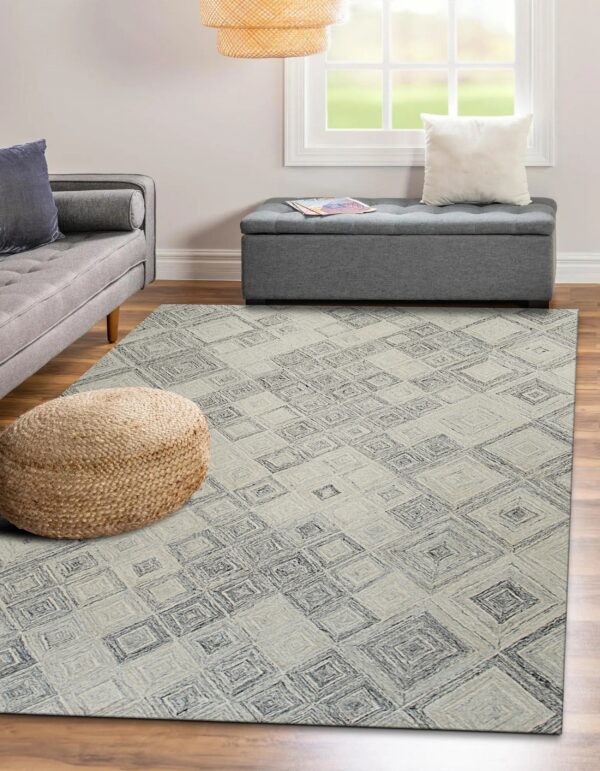Textured gray rug with dark geometric pattern lays on wood floor next to a gray sofa and woven pouf.