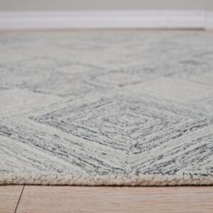 Close view of a chunky gray and cream rug featuring a geometric diamond pattern on wood flooring.