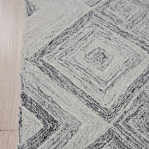 Textured white and dark gray rug featuring concentric diamond patterns rests on light wood plank flooring.