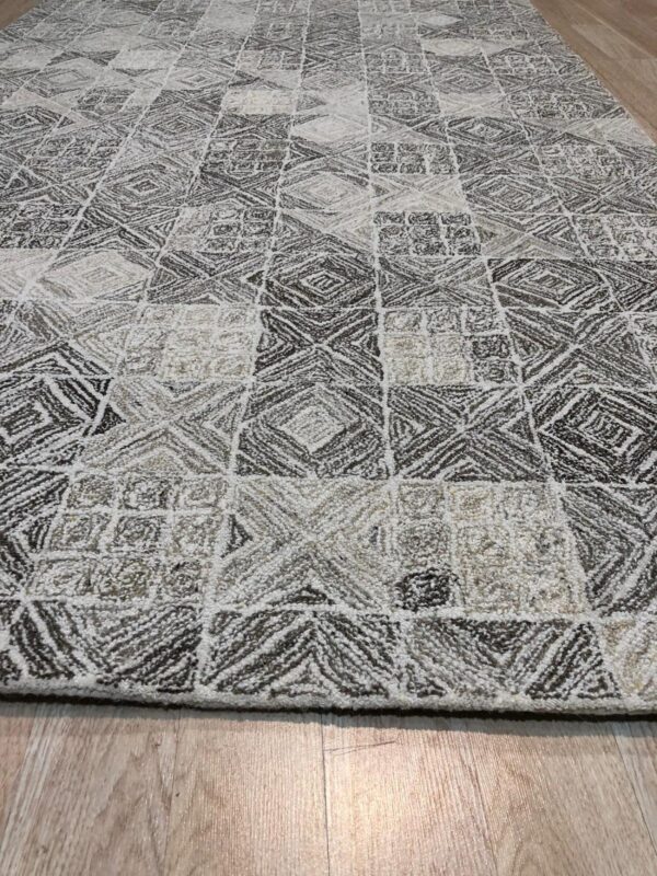 Textured neutral rug featuring alternating diamond and square patterns in white, beige, and dark gray on wood flooring.