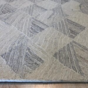 Textured cream and gray rug featuring a geometric pattern on light wood plank flooring.