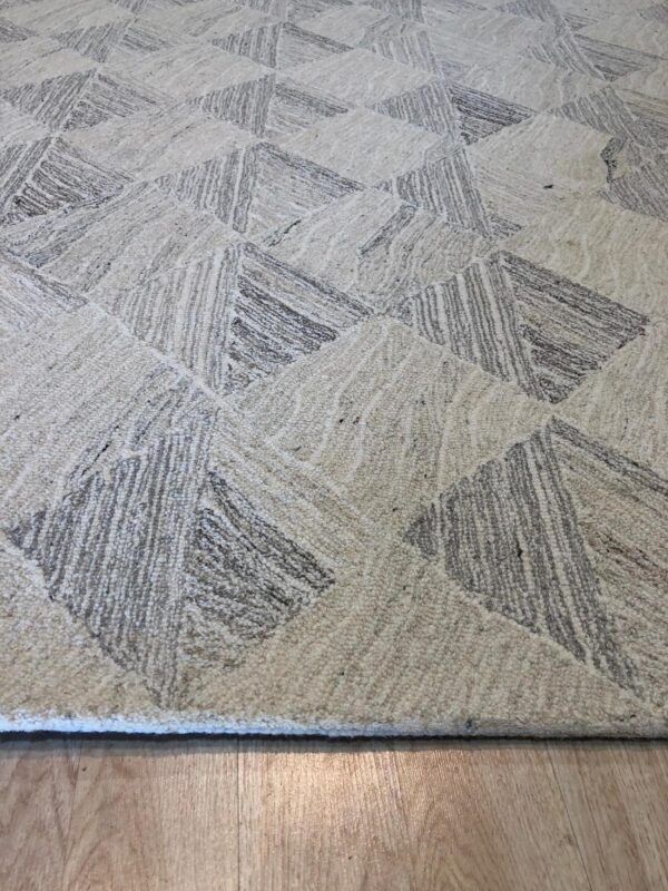 Textured cream and gray rug featuring a geometric pattern on light wood plank flooring.