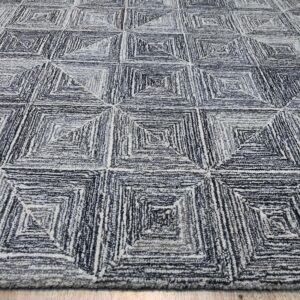 Textured gray and white rug featuring a repeating geometric pattern of concentric squares on wood flooring.