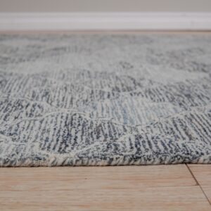 Textured blue and cream rug edge showing abstract pattern detail rests on light wood planks.