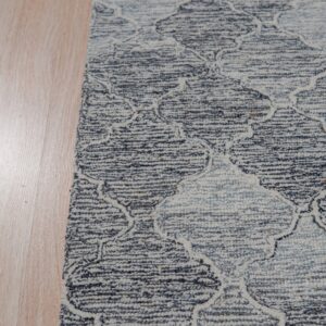 Textured blue and white rug featuring an ornate geometric pattern next to light plank flooring.