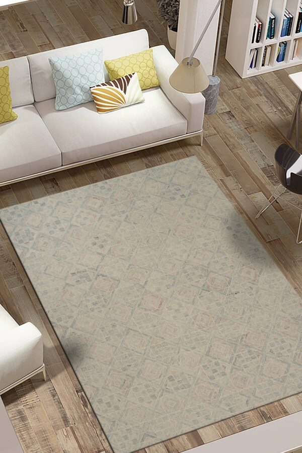 Beige rug with subtle blue and pink geometric patterns beneath a white sofa on distressed wood flooring.
