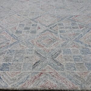 Textured off-white rug with geometric patterns in dusty blue and muted red, placed on light wood flooring.
