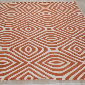 Orange and cream rug with a sculpted, repeating diamond geometric pattern rests on light wood flooring.