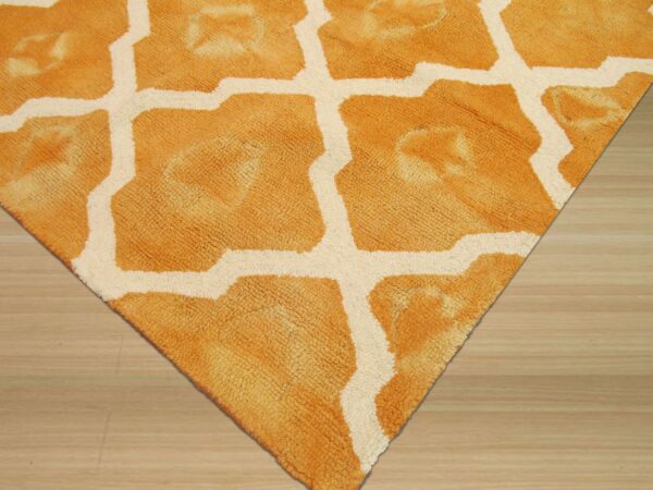A textured orange and cream moroccan lattice rug lies on light wood flooring.