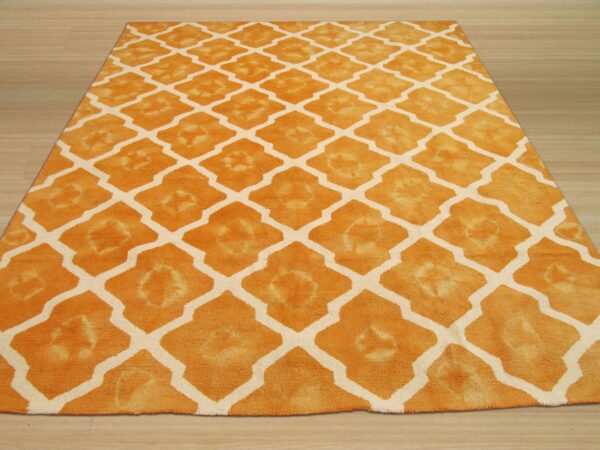 High pile orange rug featuring a geometric cream lattice design, displayed on light wooden floorboards.