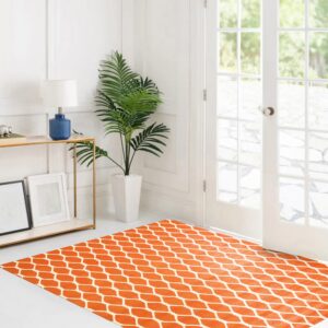 Bright orange rug featuring a white geometric trellis pattern sits on a white floor next to open French doors.