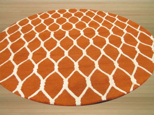 Round orange rug with a raised white geometric trellis pattern sits on light wood flooring.