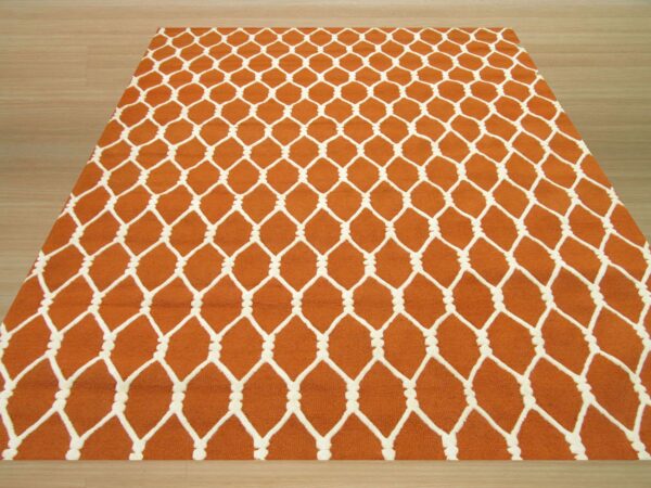 Orange rug with a chunky white knotted lattice pattern on light wood flooring.