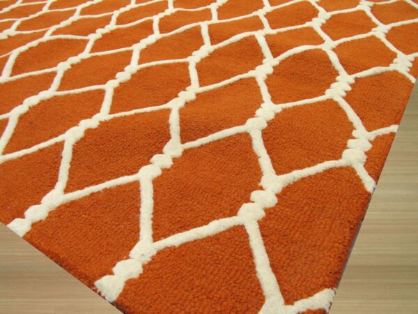 Close-up of a textured orange rug with a raised cream lattice pattern on light wood flooring.