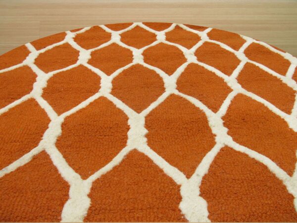 Circular rug with thick pile features a bold orange and white giraffe spot pattern on light wood floor.