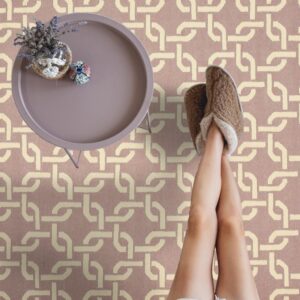 Mauve rug with a large interlocking geometric pattern in cream, viewed with legs up on a sofa.