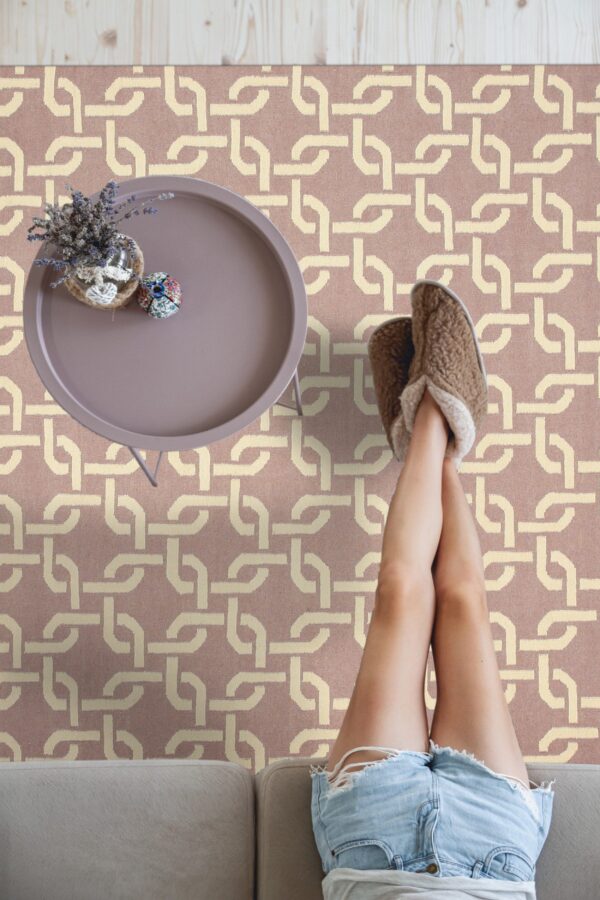 Mauve rug with a large interlocking geometric pattern in cream, viewed with legs up on a sofa.