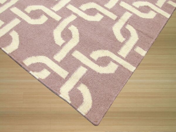 Cream interlocking geometric pattern on a low-pile mauve rug resting on light natural wood plank flooring.