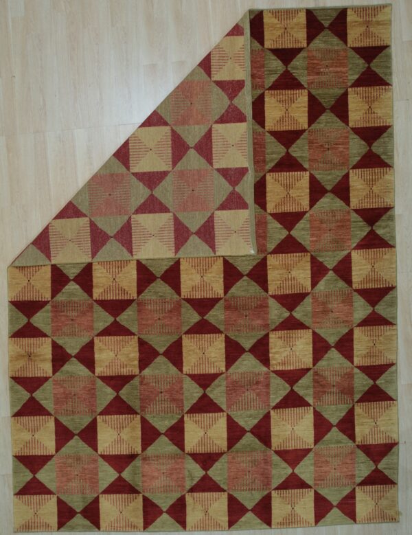 Red, sage, and tan geometric rug with repeating squares and triangles, displayed on light wood floor.