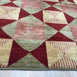 Diamond pattern rug in burgundy, sage green, and striped cream sits on light wood planks.