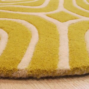 Close-up of a high-pile rug with a curving yellow-green and cream geometric pattern resting on wood flooring.