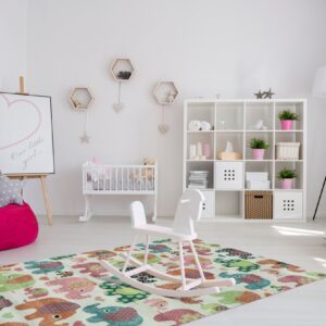 A multicolored elephant pattern rug on a light wood floor anchors a bright white nursery setting.