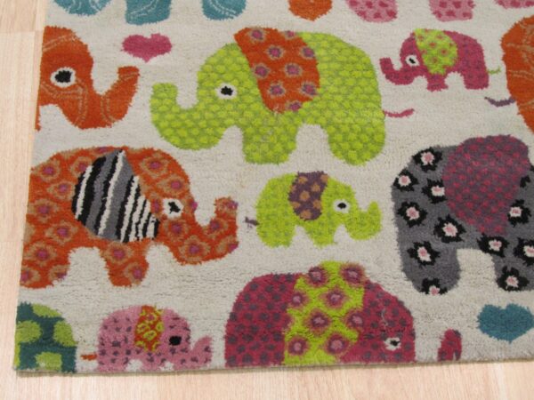 Textured rug with bright orange, lime green, pink, and gray patterned elephants on a cream background over wood floors.
