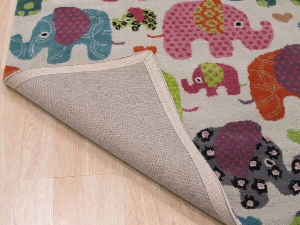 High-pile rug with colorful pink, teal, and orange elephant patterns lifted to show its backing on light wood flooring.