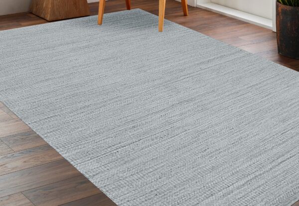 Textured silver-gray rug with horizontal woven lines covering dark wood flooring near chair legs.