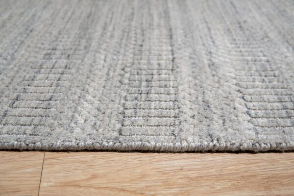 Textured light gray area rug with a raised geometric pattern visible on wood flooring.