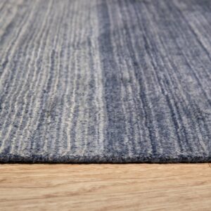 Textured blue rug with vertical cream striations viewed closely against light brown wood flooring.