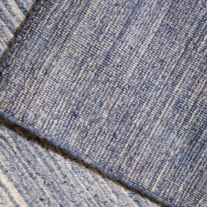 Close-up of blue rug layers revealing a dense woven backing and a low pile striped surface.
