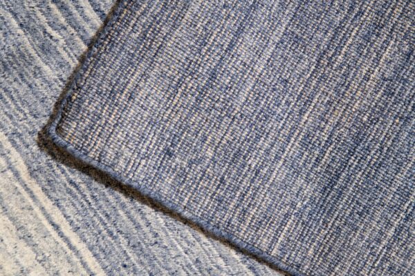 Close-up of blue rug layers revealing a dense woven backing and a low pile striped surface.