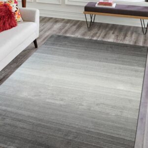 A gray ombre rug transitions from dark gray to white on distressed wood flooring beside a white sofa.