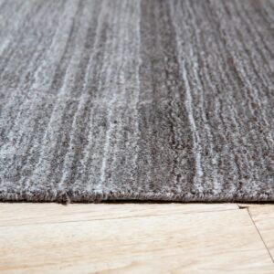 Textured gray rug with subtle striping rests on light wood plank flooring.