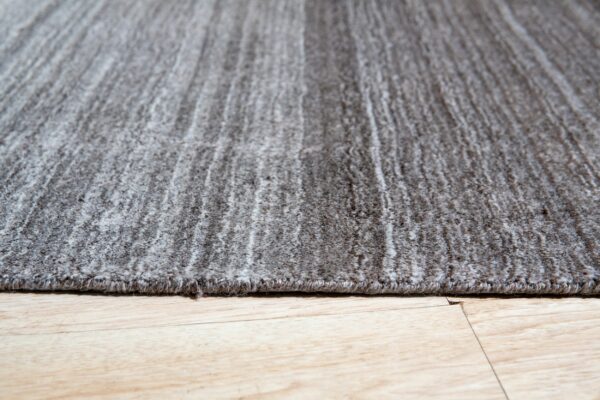 Textured gray rug with subtle striping rests on light wood plank flooring.
