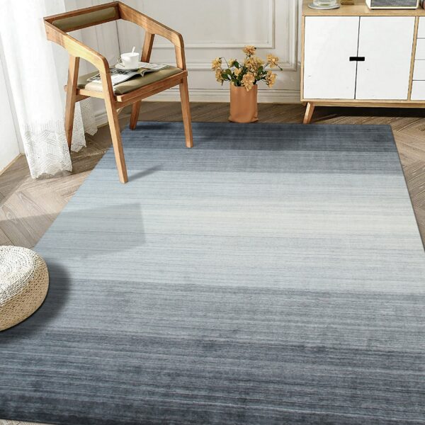 Low-pile gray and light blue striated rug creates an ombre effect under a wooden chair and cabinet.