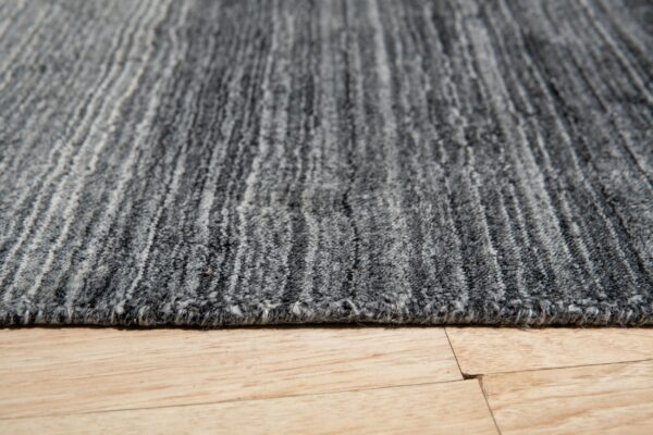 Variegated gray striped rug with medium pile texture rests on light wood plank flooring.