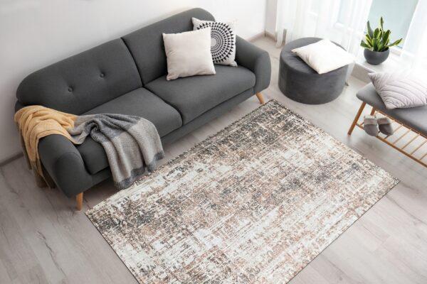An abstract gray, brown, and white area rug anchors a living room with a dark gray sofa.
