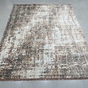 Abstract brown and cream rug with fringe displayed on a shiny gray tiled floor indoors.